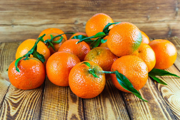 Organic mandarin orange fruits or tangerines scattered on old wooden table - Photo, Image