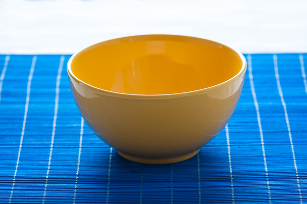 yellow bowl on the blue pad - stock photo - 写真・画像