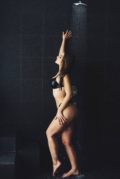 A beautiful girl is standing in the shower. Wet photo shoot - Fotó, kép