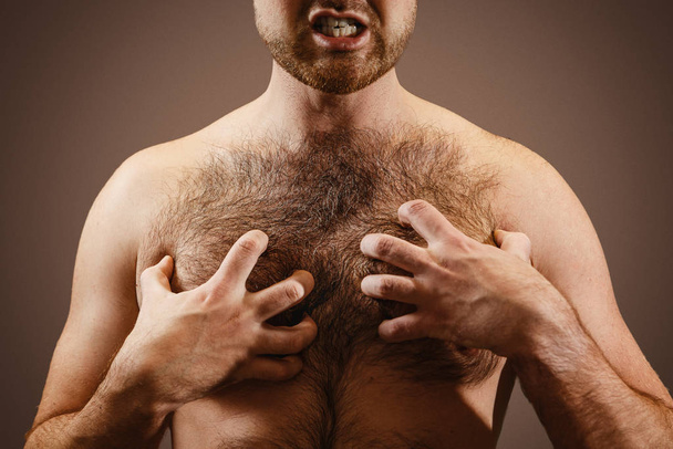 Male concept of testosterone. A man holds his hairy chest close-up - Foto, Bild