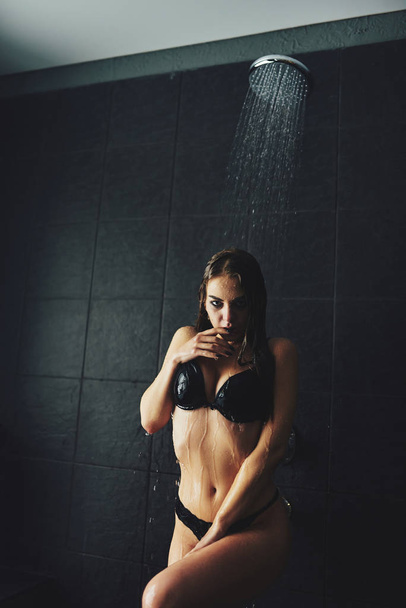 A beautiful girl is standing in the shower. Wet photo shoot - Zdjęcie, obraz