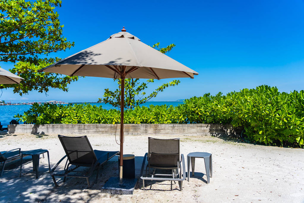 Парасолька і стілець на пляжі і морі з блакитним небом
 - Фото, зображення