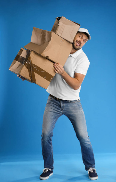 Emotional courier with damaged cardboard boxes on blue backgroun - 写真・画像