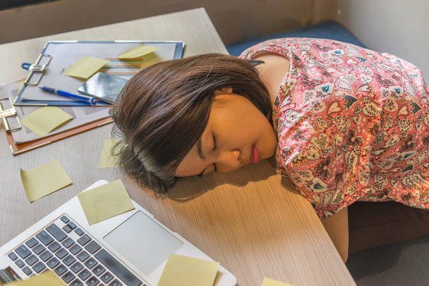 Mujer asiática durmiendo cansada en la oficina
 - Foto, imagen