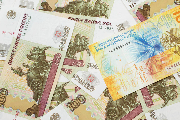 A yellow, ten Swiss franc note from Switzerland close up in macro with Russian one hundred ruble bills - Photo, Image