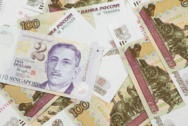 Zbliżenie wizerunek dwudolarowego banknotu od Singapuru szczelnie w makro z rosyjskimi setką rublowych banknotów - Zdjęcie, obraz