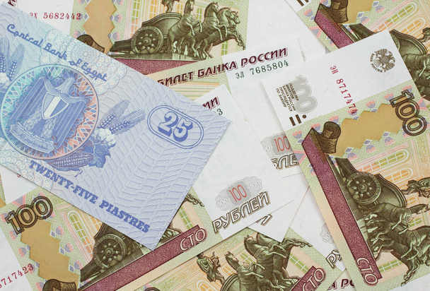 Egy közeli kép egy egyiptomi huszonöt pisatres bankjegyről orosz százrubel bankjegyekkel makróban. - Fotó, kép
