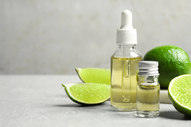 Lime essential oil and cut citrus fruits on light table. Space for text - Foto, Imagem