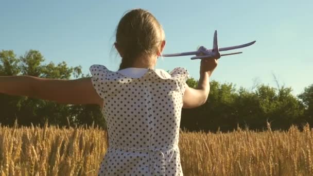 Chica feliz corre con un avión de juguete en un campo en la luz del atardecer. niños juegan juguete avión. adolescente sueña con volar y convertirse en piloto. la chica quiere convertirse en piloto y astronauta. Movimiento lento - Imágenes, Vídeo