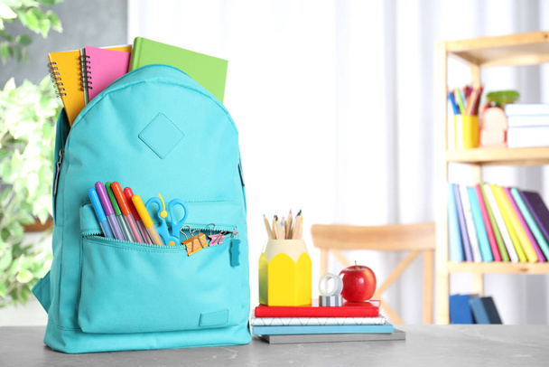 Stylish backpack with different school stationery on table indoors. Space for text - Фото, зображення