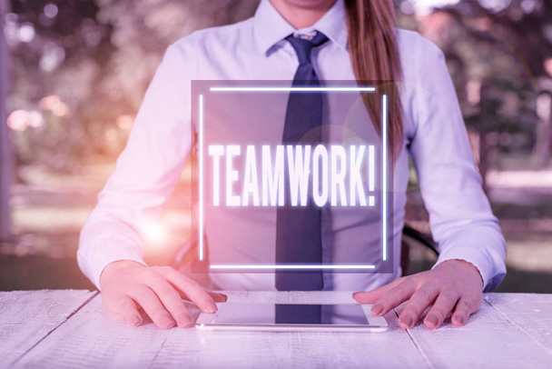 Text sign showing Teamwork. Conceptual photo combined action of group especially when effective and efficient Female business person sitting by table and holding mobile phone. - Photo, Image