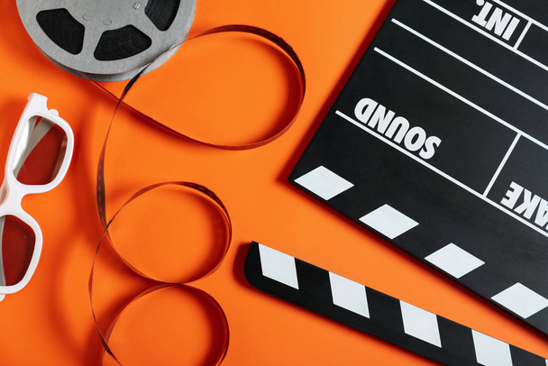 Flat lay composition with clapperboard on orange background. Cinema production - Фото, изображение