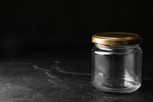 Empty glass jar on black stone table, space for text - Foto, imagen
