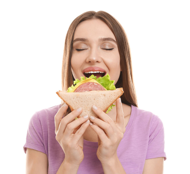 Young woman eating tasty sandwich on white background - Fotoğraf, Görsel
