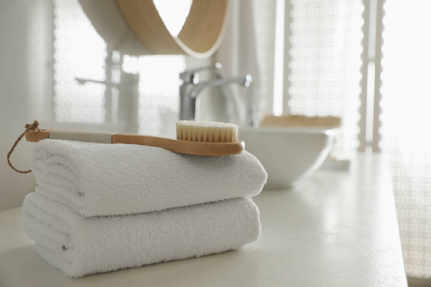 Stack of clean towels and massage brush on countertop in bathroo - Foto, immagini