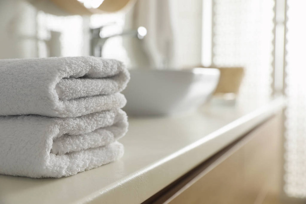 Stack of clean towels on countertop in bathroom. Space for text - Foto, Bild