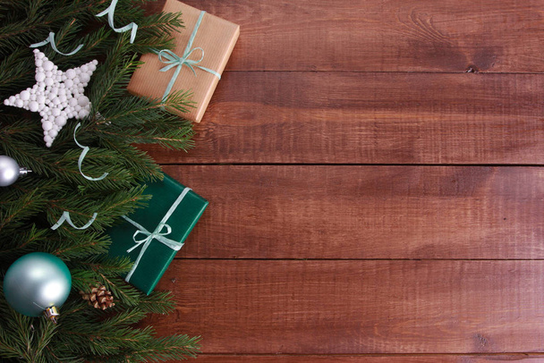 Weihnachtsgeschenke, Christbaumkugeln, Minzschlange, Tannenzweige auf dunkelbraunem Holztisch. Weihnachtlicher Hintergrund. Neues Jahr, Winterurlaub, Kopierraum, Draufsicht - Foto, Bild