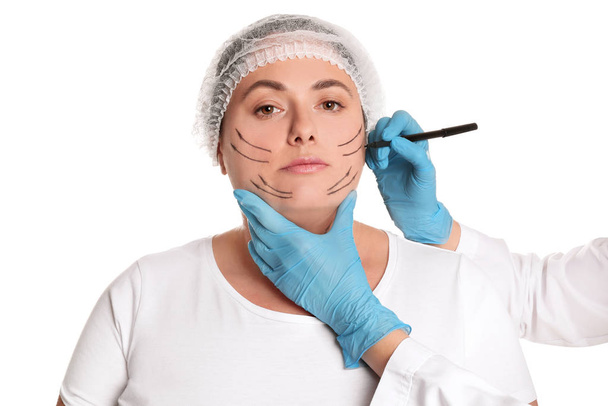 Doctor drawing marks on woman's face for cosmetic surgery operat - Valokuva, kuva