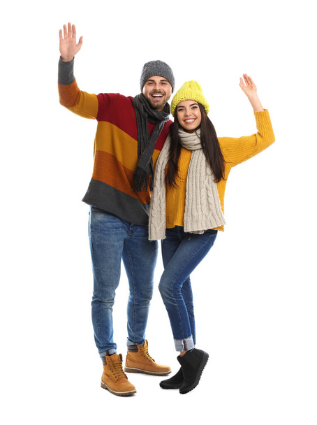Happy young couple in warm clothes on white background. Winter vacation - Фото, изображение