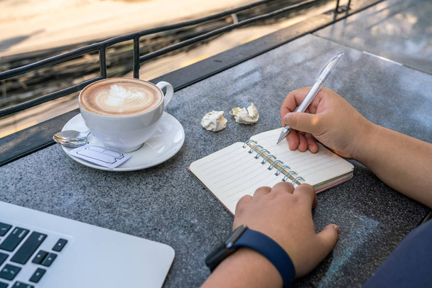 Жінка тримає ручку і пише нотатки на відкритому повітрі
 - Фото, зображення