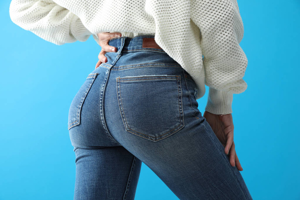 Woman wearing jeans on blue background, closeup - Fotoğraf, Görsel