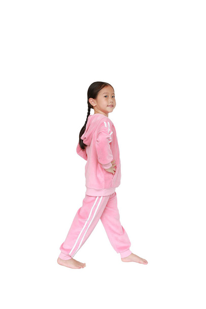 Portrait of smiling little Asian kid girl in pink tracksuit or sport cloth doing exercises isolated on white background. - Fotografie, Obrázek