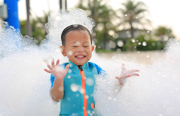 Portraits of happy little Asian baby boy smiling having fun in Foam Party at the pool outdoor. - Zdjęcie, obraz