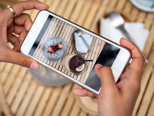 Woman's hand taking a photo of delicious chocolate tart on ceram - Фото, изображение