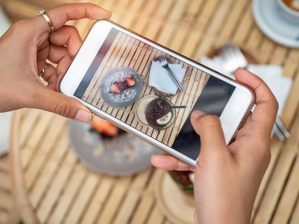 Woman's hand taking a photo of delicious chocolate tart on ceram - Fotoğraf, Görsel