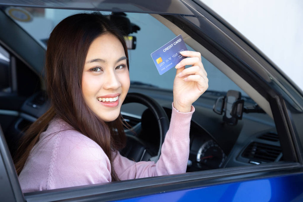 Happy krásná žena sedí uvnitř nové auto modré a ukazující kreditní kartou platit za olej, zaplatí pneumatika, údržba v garáži, provést platbu za tankování aut na čerpací stanici, auto-moto financování - Fotografie, Obrázek