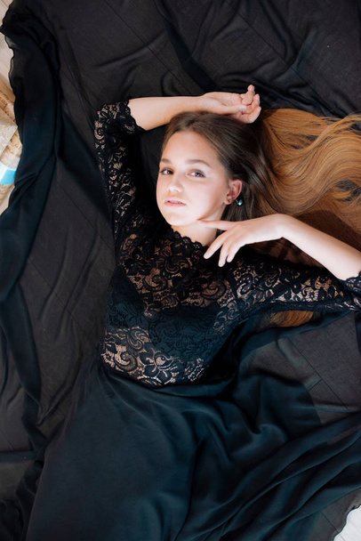 Attractive young girl with blond hair and evening make-up in an evening dress in a floor dress near a Christmas tree and a fireplace in a bright studio. New Year 2020 - Foto, Bild