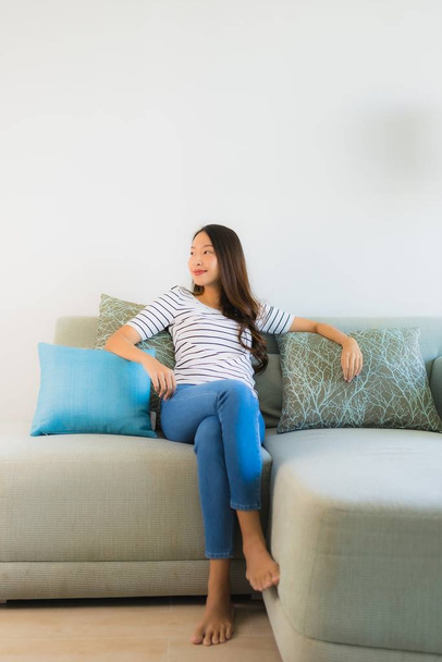 Портрет красива молода азіатка посміхається щаслива на дивані
 - Фото, зображення