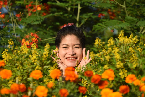 昼間は色とりどりの花を咲かせ花公園にポーズをとる若いアジア人女性の肖像   - 写真・画像