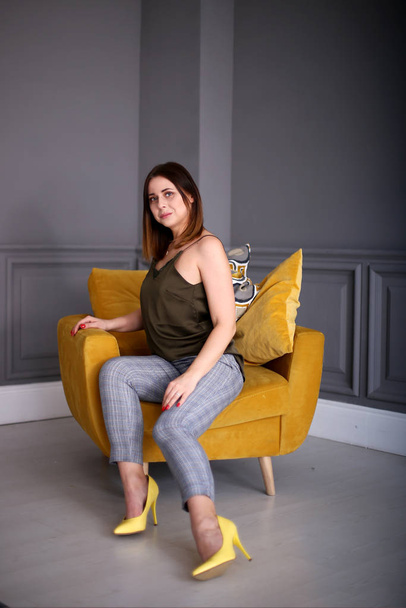 Stylish beautiful girl with a bob hairstyle sits in a yellow armchair - Foto, Imagem
