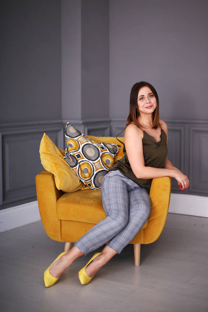 Stylish beautiful girl with a bob hairstyle sits in a yellow armchair - Photo, Image