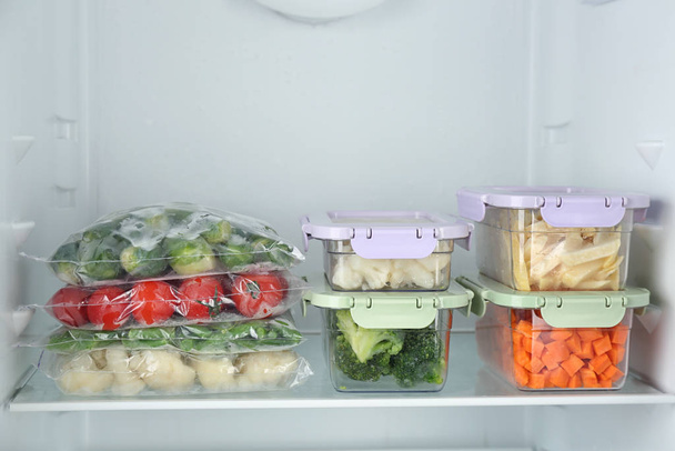 Plastic bags and containers with different frozen vegetables in refrigerator - Fotografie, Obrázek