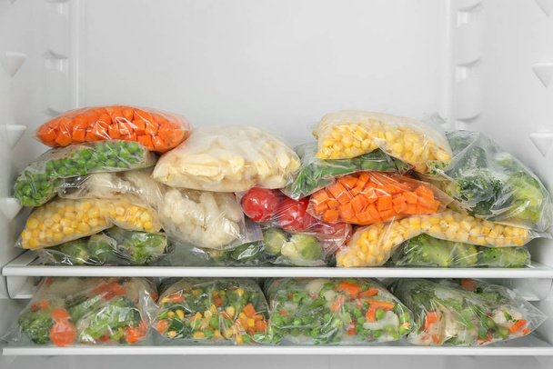 Plastic bags with different frozen vegetables in refrigerator - Zdjęcie, obraz