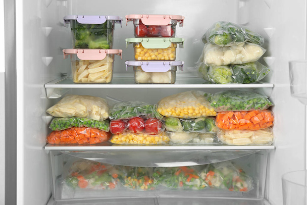 Plastic bags and containers with different frozen vegetables in refrigerator - Zdjęcie, obraz