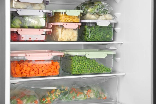 Plastic bags and containers with different frozen vegetables in refrigerator - Fotografie, Obrázek