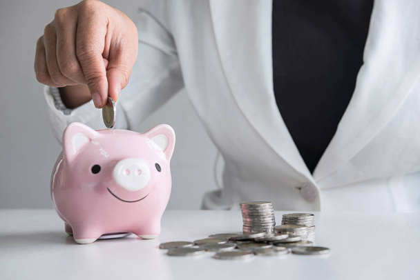 Business woman putting coin into pink piggy bank for planning st - Photo, Image