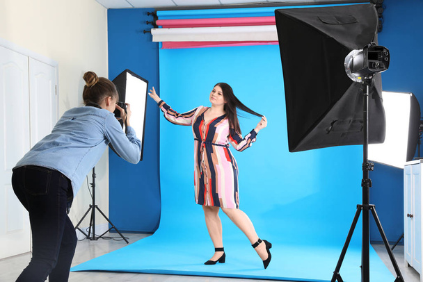 Photographer taking picture of overweight woman in studio. Plus size model - Fotó, kép