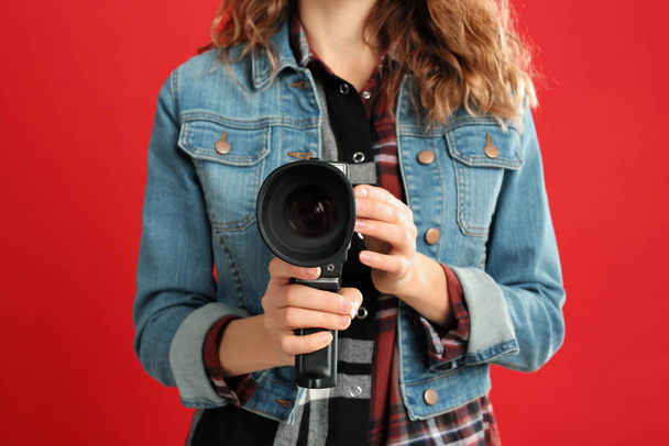Woman with vintage video camera on red background, closeup - Φωτογραφία, εικόνα