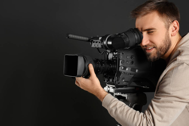 Operator with professional video camera on black background - Valokuva, kuva