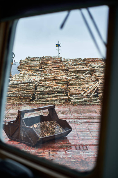 Husum / Σουηδία - 7.05.2019: Εκφόρτωση φορτίου ξυλείας στο λιμάνι Husum. Φόρτωση ξυλείας σε φορτηγό με γερανό ξηράς. Θολούρα.  - Φωτογραφία, εικόνα