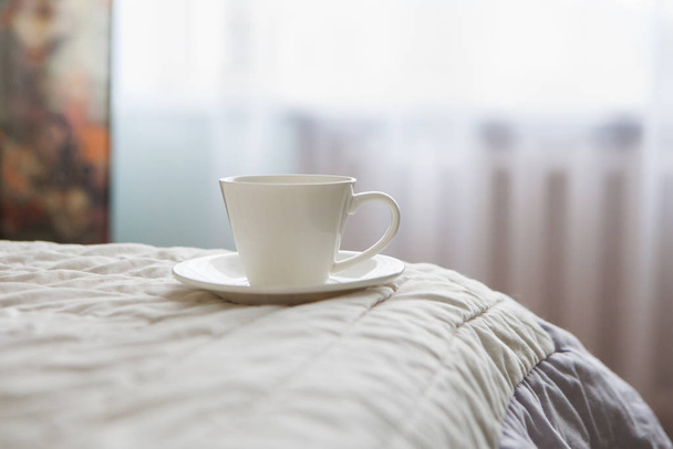 morning cup of coffee on the background of the bed and the window - Photo, image