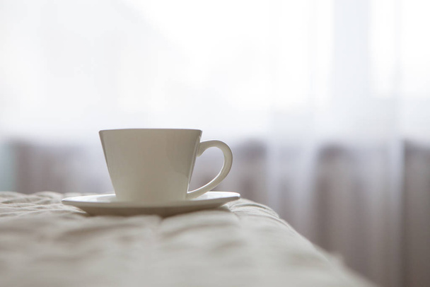 morning cup of coffee on the background of the bed and the window - Φωτογραφία, εικόνα