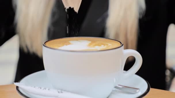 Unrecognized blonde woman falls asleep sugar in a cup of coffee, cappucino from stick. The concept of combating diabetes, obesity, overweight, dietary nutrition - Filmati, video