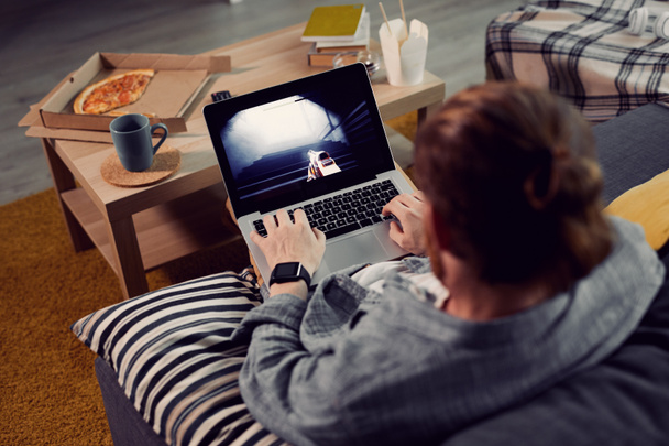 Magas látószögű kilátás felismerhetetlen férfi videojátékokat játszik laptopon keresztül, miközben pihentető otthon - Fotó, kép