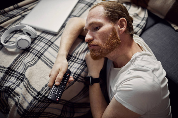 Vysoký úhel pohledu na dospělého muže spícího na pohovce při sledování televize v noci, kopírovat prostor - Fotografie, Obrázek