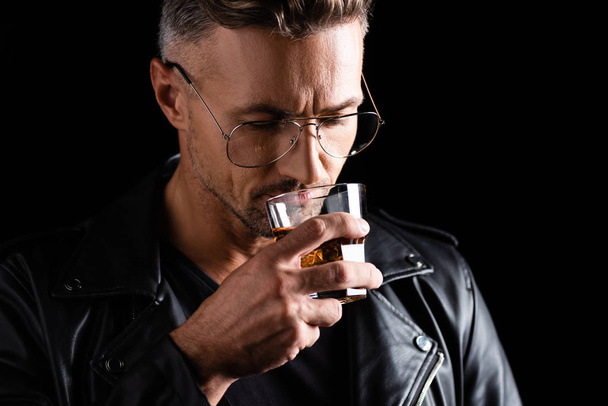 Handsome man in sunglasses drinking whiskey isolated on black - Foto, Imagem